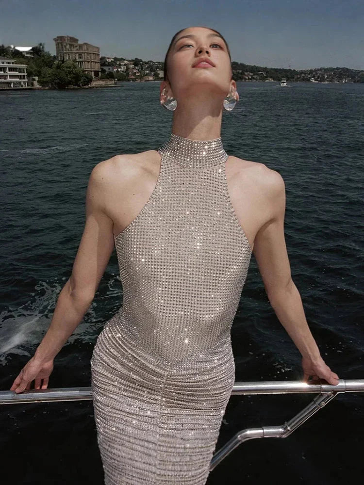 Woman wearing sexy halter neck backless diamonds sleeveless shiny crystal dress on a boat.